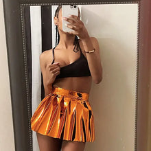 Cargar imagen en el visor de la galería, Fashionable model wearing a shiny metallic pleated mini skirt and black crop top, capturing a stylish mirror selfie.