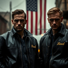 Load image into Gallery viewer, Two men in dark jackets with 'Reed' embroidered on them, standing in front of an American flag.