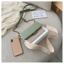 Load image into Gallery viewer, Designer leather crossbody shopping bag with a mint green flap, beige straps, and a nearby smartphone on a cream couch.