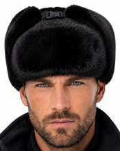 Load image into Gallery viewer, A close-up of a man wearing a black faux-fur ushanka hat with a black collar and a black jacket against a white background.