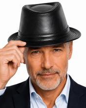 Load image into Gallery viewer, A close-up portrait of a man wearing a black leather fedora hat, tipping it with his right hand. He is wearing a light blue dress shirt and a dark navy suit jacket, set against a solid white background.