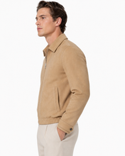 Charger l'image dans la galerie, A man in side profile wearing a tan suede jacket and off-white trousers, photographed against a clean white studio background.