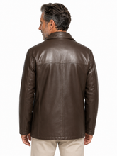 Cargar imagen en el visor de la galería, A man viewed from the back wearing a dark brown leather jacket and light beige pants, photographed against a plain white studio background.