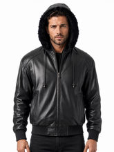 Cargar imagen en el visor de la galería, A man wearing a black faux-leather hooded jacket with a dark faux-fur trimmed hood, front zipper, and ribbed knit cuffs and hem, photographed against a plain white background.