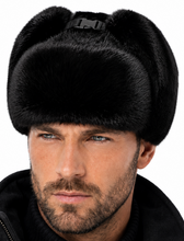Load image into Gallery viewer, A man wearing a black faux fur ushanka hat with a black buckle strap, shown in a close-up portrait against a white background.