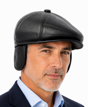 Load image into Gallery viewer, A man wearing a black leather flat cap with ear flaps, styled with a navy blazer and light blue dress shirt, against a solid white background.