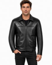 Charger l'image dans la galerie, A man wearing a black leather jacket with a front zipper, collar, and zippered hand pockets, paired with a black t-shirt and black jeans, against a plain white background.