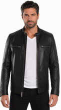 Load image into Gallery viewer, A man wearing a black leather motorcycle jacket over a white t-shirt and black pants, photographed against a plain white studio background.