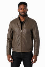 Cargar imagen en el visor de la galería, A man wearing a brown leather jacket with a front zipper, zippered chest pockets, and ribbed cuffs, paired with black jeans, against a plain white background.