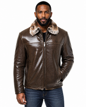 Cargar imagen en el visor de la galería, A man wearing a brown textured leather aviator-style jacket with a plush tan and brown faux-fur collar, paired with blue jeans, against a plain white background.