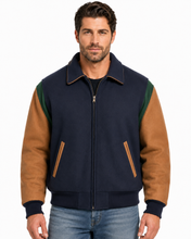 Load image into Gallery viewer, A man wearing a color-blocked wool-blend bomber jacket with a navy blue body, tan sleeves, and green shoulder panels, paired with blue jeans against a white studio background.