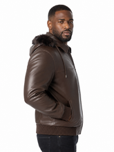 Load image into Gallery viewer, A man wearing a dark brown leather hooded jacket with a faux-fur trimmed hood, shown in profile against a plain white background.