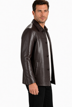 Charger l'image dans la galerie, A man wearing a dark brown leather jacket over a white collared shirt and black pants, shown in a side profile against a plain white studio background.