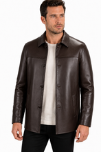 Charger l'image dans la galerie, A man wearing a dark brown leather jacket over a white t-shirt and black pants, photographed against a plain white studio background.
