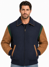 Load image into Gallery viewer, A man wearing a navy blue and brown color-blocked bomber jacket with green shoulder panels, paired with blue jeans, against a plain white background.