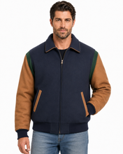 Load image into Gallery viewer, A man wearing a navy blue and brown color-blocked zip-up jacket with green shoulder panels, paired with blue jeans, against a plain white background.