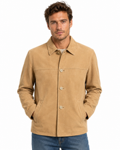 Cargar imagen en el visor de la galería, A man wearing a tan suede jacket with a button-up front and chest pockets, paired with blue jeans, against a plain white background.
