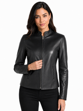 Cargar imagen en el visor de la galería, A woman modeling a black real -leather jacket with a stand collar and front zipper, paired with black pants, against a plain white background.