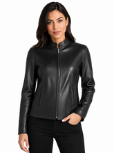 Cargar imagen en el visor de la galería, A woman modeling a black real -leather jacket with a stand collar and front zipper, paired with black pants, against a plain white background.