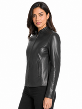 Cargar imagen en el visor de la galería, A woman modeling a black real -leather moto jacket with a mock neck and front zipper, shown against a plain white background.