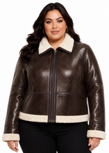 Cargar imagen en el visor de la galería, A woman modeling a brown textured real-leather jacket with a cream sherpa collar, hem, and cuffs, paired with black pants against a white background.