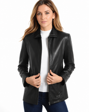 Cargar imagen en el visor de la galería, A woman wearing a black real leather jacket over a white top and dark blue jeans, photographed against a plain white background.