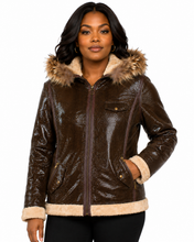 Cargar imagen en el visor de la galería, A woman wearing a brown real-leather hooded jacket with a beige faux-fur trimmed hood and cuffs, photographed against a plain white background.