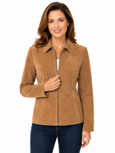 Cargar imagen en el visor de la galería, A woman wearing a tan suede zip-front jacket with a pointed collar and long sleeves, paired with dark blue jeans, against a plain white background.