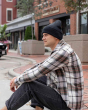 Charger l'image dans la galerie, Person wearing CS101 HAAKWEAR Traditional Silent Cuffed Beanie, Midnight Black sitting on city sidewalk.