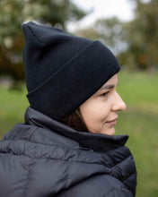 Charger l'image dans la galerie, Person wearing CS101 HAAKWEAR Traditional Silent Cuffed Beanie, Midnight Black, outdoors with greenery in the background.