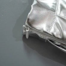 Cargar imagen en el visor de la galería, Close-up of the metallic pleated faux leather mini skirt zipper detail, showcasing sleek design and sophisticated texture.