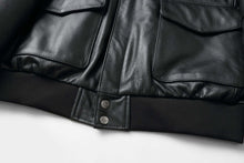 Load image into Gallery viewer, Close-up of REED Men's Premium Leather Aviator Bomber Jacket showcasing black leather and details of front envelope pockets.