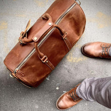 Load image into Gallery viewer, The Dagny Weekender | Large Leather Duffle Bag with elegant design on concrete surface with stylish brown shoes.