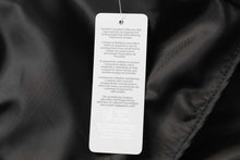 Load image into Gallery viewer, Care label inside black jacket with multilingual washing and care instructions.