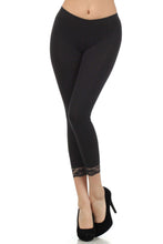 Load image into Gallery viewer, Model wearing black cotton blend lace trim stretch capri leggings, USA-made, perfect for yoga or casual wear. Features 2-inch lace trim.