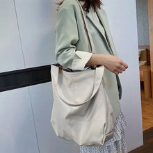 Charger l'image dans la galerie, Woman carrying a soft vegan leather shoulder bag with large capacity, showcasing luxury and elegance in a light indoor setting.