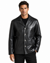 Cargar imagen en el visor de la galería, A man wearing a black leather jacket with silver-tone snap buttons over a black shirt and black pants, photographed against a plain white studio background.