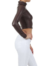 Load image into Gallery viewer, Side view of a woman wearing a matte liquid mock neck turtleneck long sleeve crop top in dark brown, paired with white pants.
