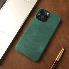 Cargar imagen en el visor de la galería, Green genuine leather iPhone case with vintage aesthetic on a desk beside a laptop and pen.
