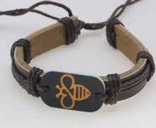 Cargar imagen en el visor de la galería, Dark brown bracelet with carved bee emblem showcased on a thick leather band, featuring rustic charm and artisanal design.