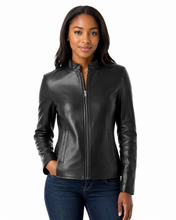 Cargar imagen en el visor de la galería, A woman modeling a black real-leather zip-up jacket with a stand collar and side zip pockets, paired with dark blue jeans, against a plain white background.