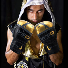 Load image into Gallery viewer, Adult in gold and black kickboxing gloves poised for training, showcasing premium PU leather build for durability and comfort.