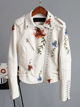 Cargar imagen en el visor de la galería, Floral print faux leather jacket with punk rock stud details and romantic embroidery, hanging on a wooden hanger.