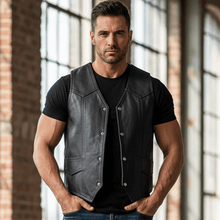 Load image into Gallery viewer, Man wearing a black leather vest, black t-shirt, and blue jeans standing in a sunlit room with large windows and brick walls.