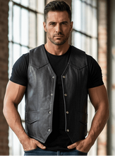 Load image into Gallery viewer, Man wearing a black leather vest, black t-shirt, and blue jeans standing in a sunlit room with large windows and brick walls.