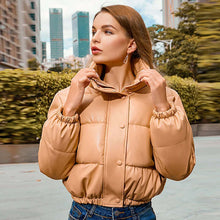 Load image into Gallery viewer, Woman wearing a stylish winter thick PU leather coat in urban setting, showcasing chic cold-weather fashion.