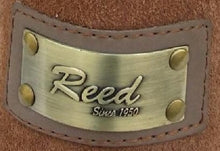 Cargar imagen en el visor de la galería, Close-up of Reed bronze label on brown suede leather surface with 'Since 1950' engraving