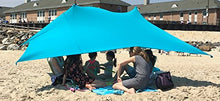 Load image into Gallery viewer, Group enjoying shade under eZthings UV light beach shelter with sandbag anchors on a sunny beach.