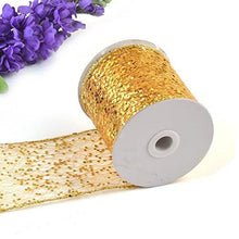 Load image into Gallery viewer, Gold sparkly sheer fabric ribbon on a spool, ideal for party decor, gift baskets, and craft projects, with purple flowers in the background.