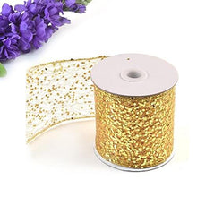 Load image into Gallery viewer, Gold sparkly sheer fabric ribbon on spool, ideal for gift wrapping, party decor, and craft projects, shown with purple flowers.